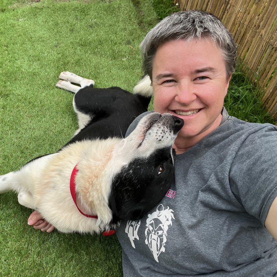 Tex lying relaxed on the grass with head resting against Caroline, who is smiling